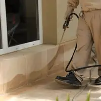 General pest control technician spraying exterior perimeter around a home in Wilmington, NC