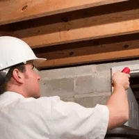 Termite inspection technician checking a basement wall and framing for termite activity in Wilmington, NC